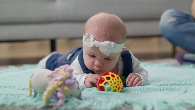 Little girl kid plays a rattle on the floor with parents