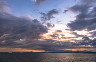 Fototapeta premium Sunset and dramatic set of clouds drifting over the tropical waters of the Caribbean Sea are lit by the last moments of daylight