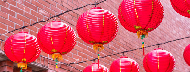 Fototapeta na wymiar Beautiful round red lantern hanging on old traditional street, concept of Chinese lunar new year festival, close up. The undering word means blessing.