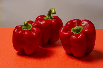 Three fresh red bell peppers on red board  