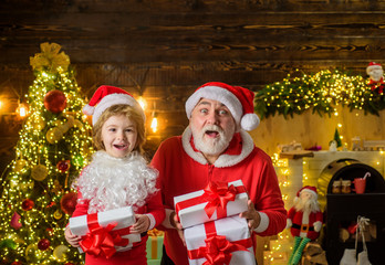 Fototapeta na wymiar Santa Claus and child with Christmas present. Family holidays and childhood concept. Little child with Santa Claus and Christmas gift at home. Kid boy and father in Santa costume and beard. Christmas.
