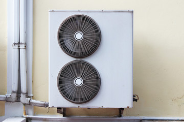A compressor of air conditioner placed on the wall outside the building