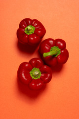 Top view of three fresh red bell peppers on red background  