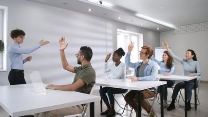 Full arc shot of group of multicultural university students sitting at desk in front of transparent touchscreen tablets and raising hands, and female lecturer asking questions. Suitable for AR, VR. - Powered by Adobe