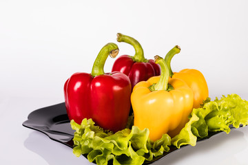 Red and yellow bell peppers with lettuce on a plate. Cooking a vegetarian dish.