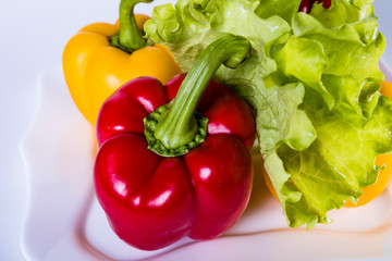 Red and yellow bell peppers with lettuce on a plate. Cooking a vegetarian dish.