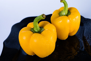 Yellow pepper on a black plate on a white background. Yellow bell pepper.