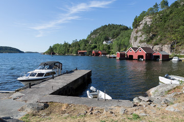 kleine Yacht und rote Bootshäuser am Hafen von Svennevik, Südnorwegen