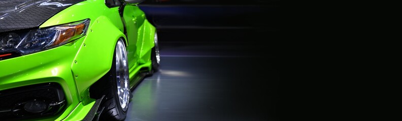 Fototapeta Front headlights of green modify car on black background,copy space obraz