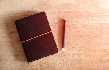 Notepad and pen on the wooden desk in warm tone.