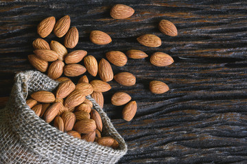 Closeup almonds on wooden texture on dark background.