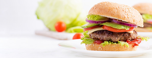 Big sandwich - hamburger burger with beef, avocado, tomato and red onions on light background....