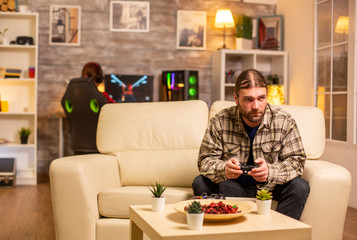 Male gamer playing video games on a console in the living room