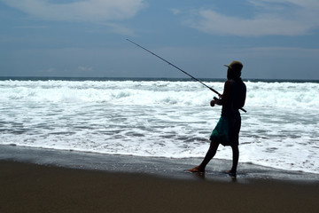 Fisherman is fishing in a beach
