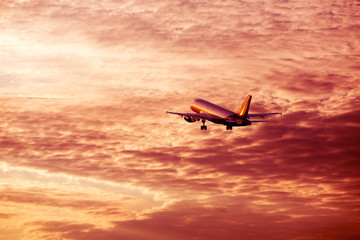 Fototapeta na wymiar Airplane flying away in awesome cloudy sunset sky