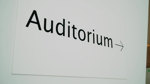 sign indicating the audience. on the white wall in black letters the auditorium is written