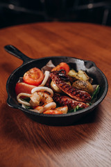 Hot pan with Indonesian octopus with langoustines, squid and baked potatoes with honey-mustard sauce