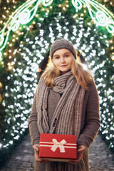 Girl holding gift box on winter festival. Happy woman with Christmas gift over Christmas background.