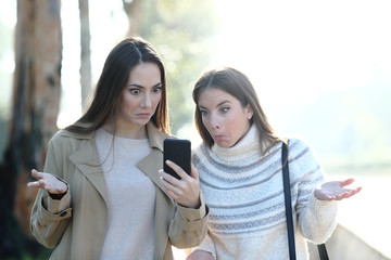 Perplexed women checking mobile phone content