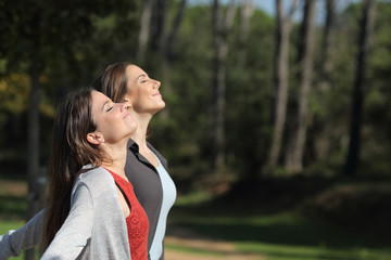 Two relaxed women breathing deeply fresh air in a park.jpg