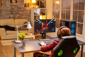 Back view of female gamer playing on powerful computer PC late at night in the living room © DC Studio