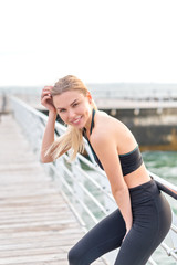 Smiling young beautiful girl with long hair in sportswear on the backgroung of the sea