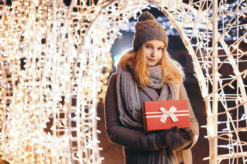 Girl holding gift box on winter festival. Happy woman with Christmas gift over Christmas background.