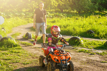 Father and daughter playing on the road at the day time. They driving on quad bike in the park. People having fun on the nature. Concept of friendly family. © Angelov