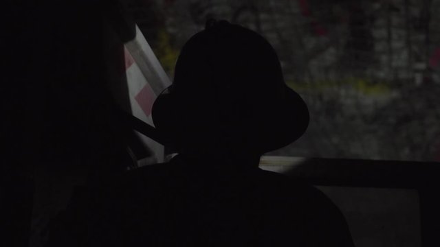 Silhouette of person wearing hard hat working underground operating heavy machinery
