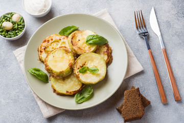 Slices of fried zucchini in batter with garlic and Basil on a plate.