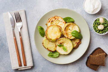 Slices of fried zucchini in batter with garlic and Basil on a plate.