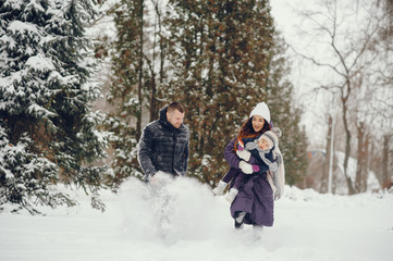 Fototapeta na wymiar Family have fun in a winter park. Stylish mother in a purple jacket. Little girl in a winter clothes. Father with cute daughter