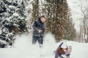 Family have fun in a winter park. Stylish mother in a purple jacket. Little girl in a winter clothes. Father with cute daughter