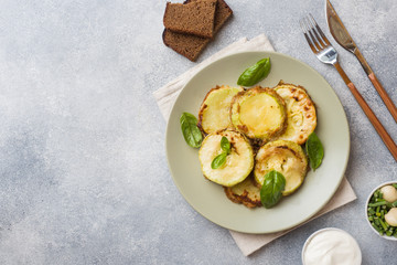 Slices of fried zucchini in batter with garlic and Basil on a plate.