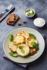Slices of fried zucchini in batter with garlic and Basil on a plate.