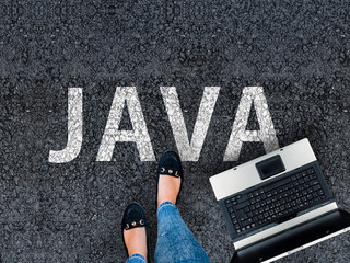 Java programming language. woman legs in sneakers standing next to laptop and word java on asphalt