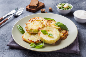 Slices of fried zucchini in batter with garlic and Basil on a plate.