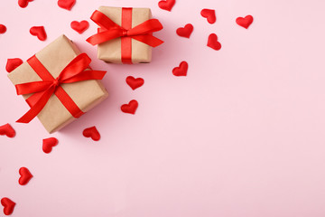 Presents with red bow on pink background with heart confetti. Flat lay style. Valentine day concept
