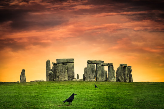 Historic Stonehenge under colorful sunset with black crows
