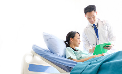Obraz premium Asian Male doctor is talking to female patients lie in bed in the hospital room about the diagnosis of her illness.disease treatment and health care concept