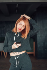 Fototapeta premium European white redhead woman hold smartphone indoor