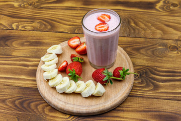 Glass of fresh smoothie of strawberry and banana on a wooden table