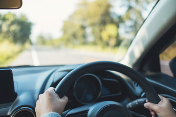 Closeup image of a woman holding steering wheel while driving a car on the road