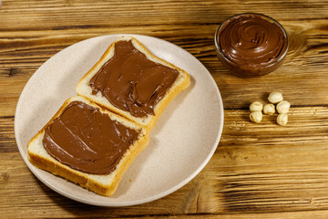 Two slices of bread with delicious chocolate hazelnut spread on wooden table