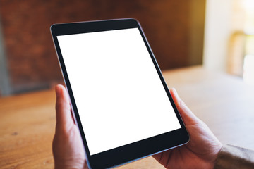 Mockup image of a woman sitting and holding black tablet pc with blank white desktop screen