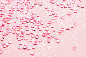 Pink glitter and sequins on a pastel pink background - selective focus