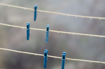 Clothespins on empty clothesline. 5 plastic blue clothespins on clotheslines with raindrops. Cloudy...