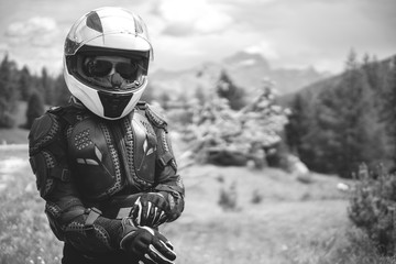 Close up of girl dressed in protective suit of body armor, tutle prtotective jacket, with helmet and glowes. Mountains view on background. Outdoors. Black and white, copy space, selective focus