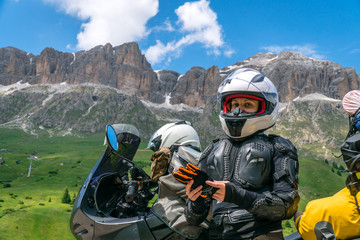 Close up portrait of motorcycle lady with she adventure motorbike on the top mountain, enduro, off road, beautiful view, danger road in mountains, freedom, extreme vacation. Passo Pordoi, Italy