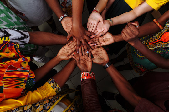 Hands of a happy group of multinational African, Latin American and European people who stay together in a circle. Team leader, peace concept